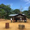 Men sitting under roofed shelter in the Gabonese village of Massaha. Image courtesy Graden Froese.