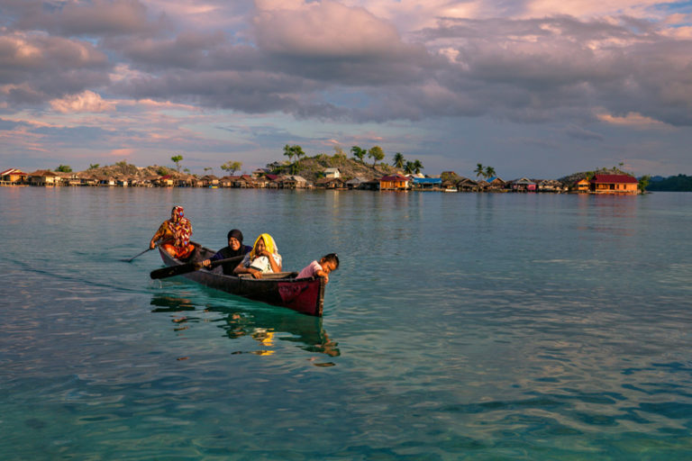 Bajo women canoeing from the village to a tourist beach.