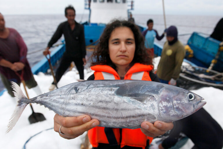 Farah Obaidullah holds a fish on a fishing boat.