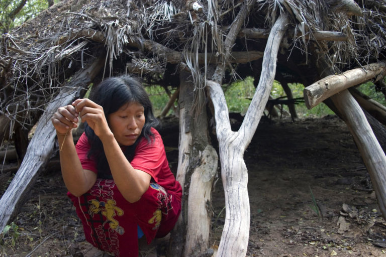 Guireja, an Ayoreo woman, sits outside her house that she was forced to abandon as a result of logging, Paraguay. Image by Survival.