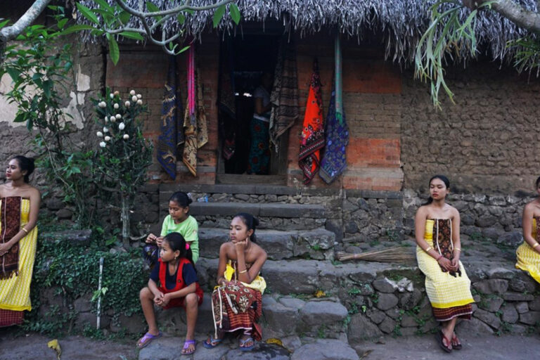 Women from a village in Bali in front of a house that preserves the traditional architecture with earthen wall on the front.