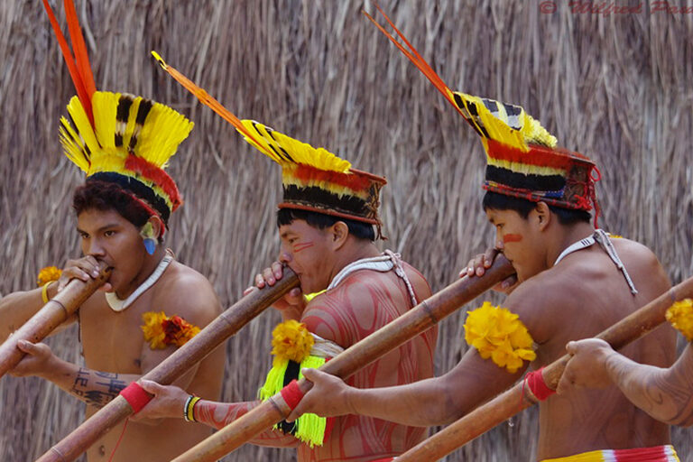 Kuikuro men playing flutes.