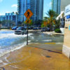 High tide flooding in downtown Miami. The useful life of roads and other infrastructure is shortened dramatically by repeated saltwater inundation. Image via Wikimedia Commons.