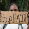 Person holding cardboard sign saying Stop EACOP", concealing lower half of their face. Photothèque AT via Flickr (CC BY-NC 2.0)